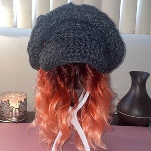Knitted oversized grey wool cap w/ brown leather buttons on each side of brim.